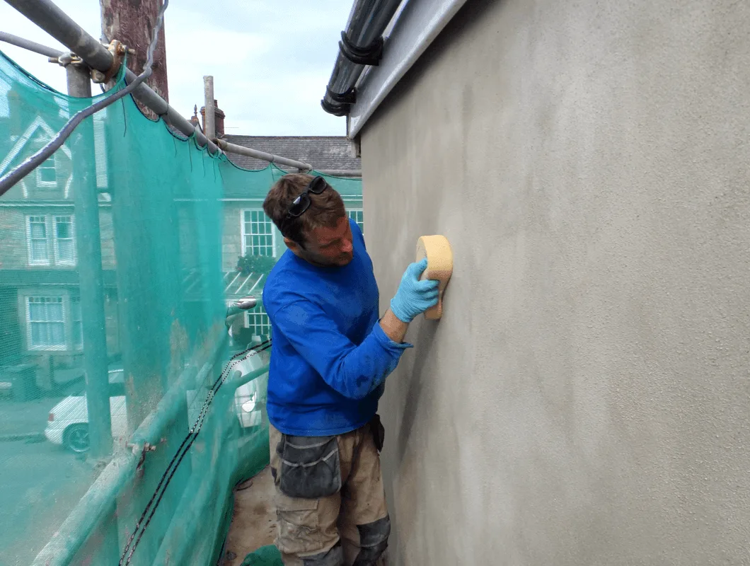 JCS Page applying lime render to a wall, drawing on hands-on building experience