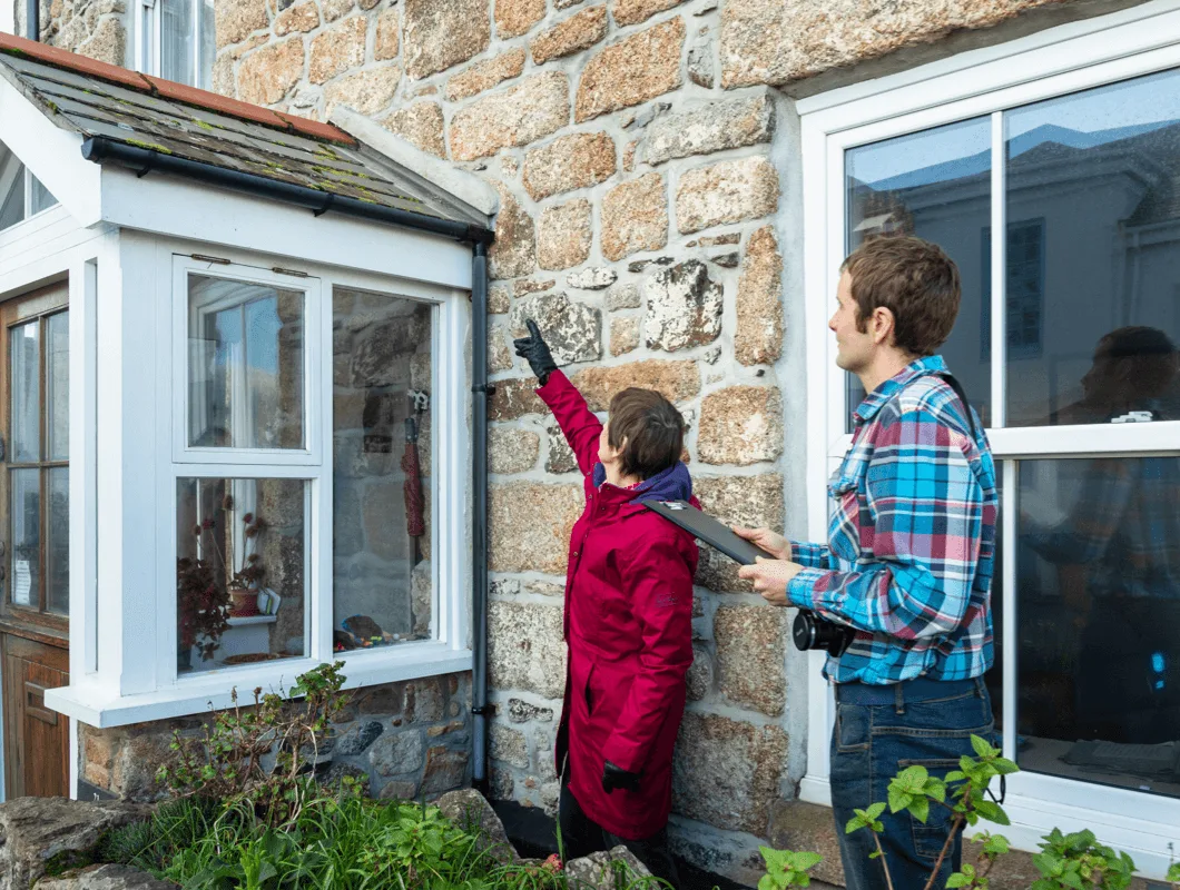 Two people reviewing maintenance advice for a Cornish cottage's stonework
