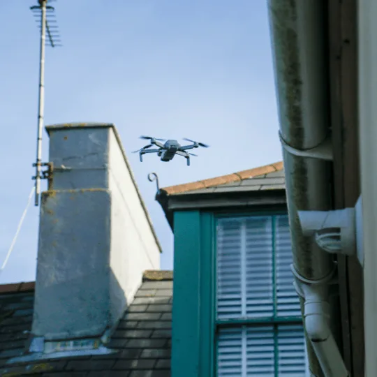 Survey drone flying close to a chimney stack and dormer window